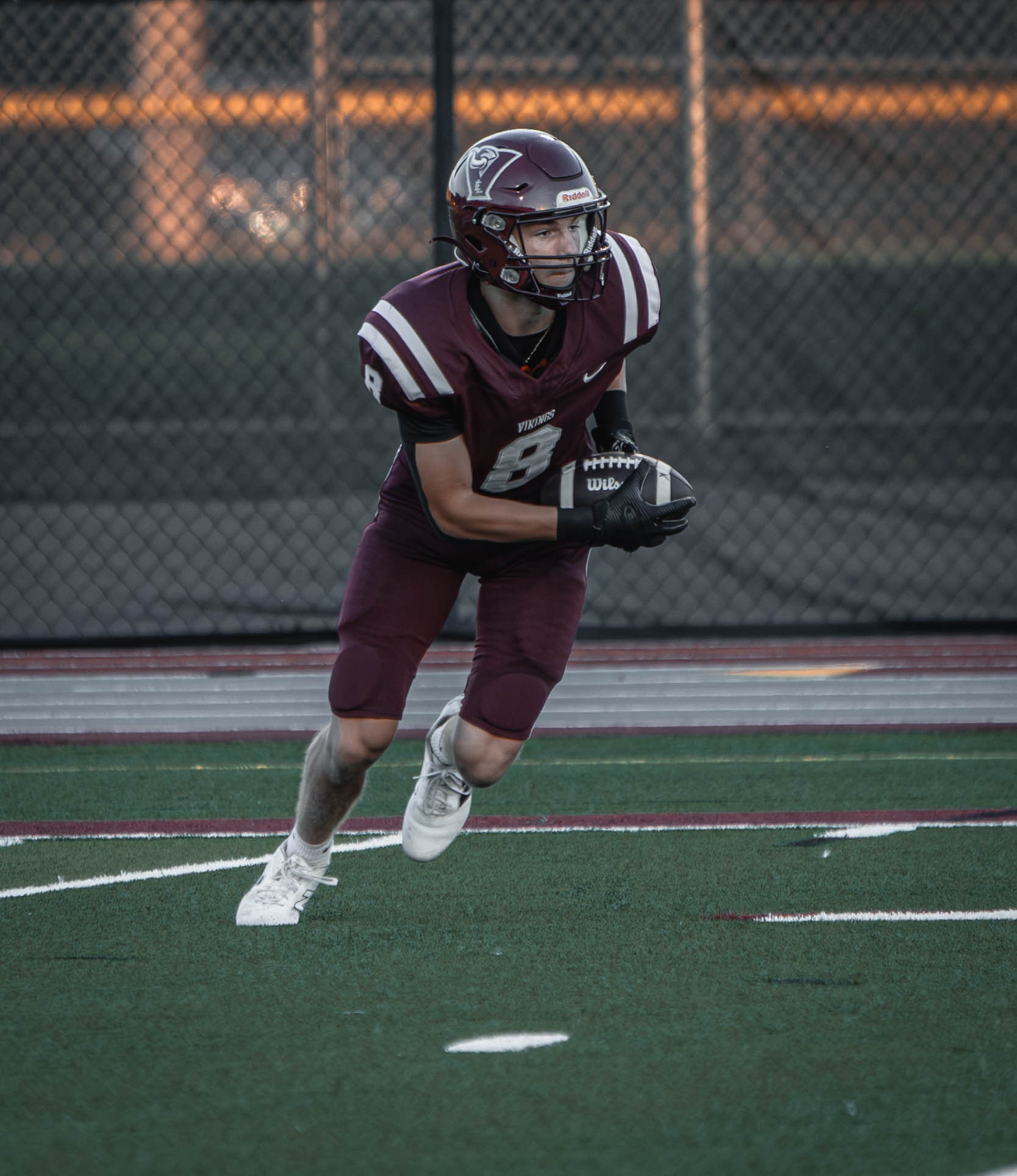 East Lyme number 8 carrying the football and cutting upfield at dusk