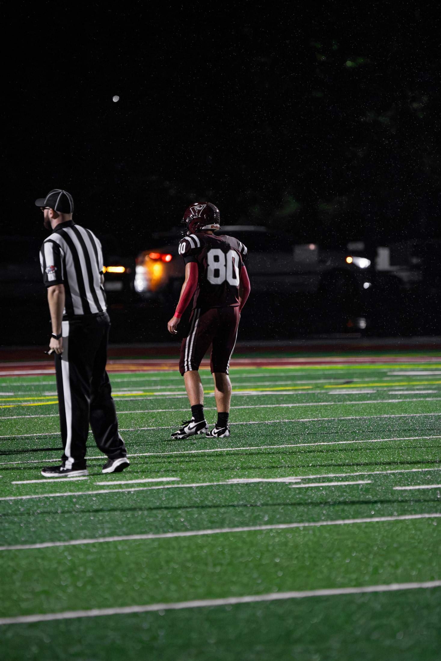 East Lyme number 80 standing near a referee on a rainy field