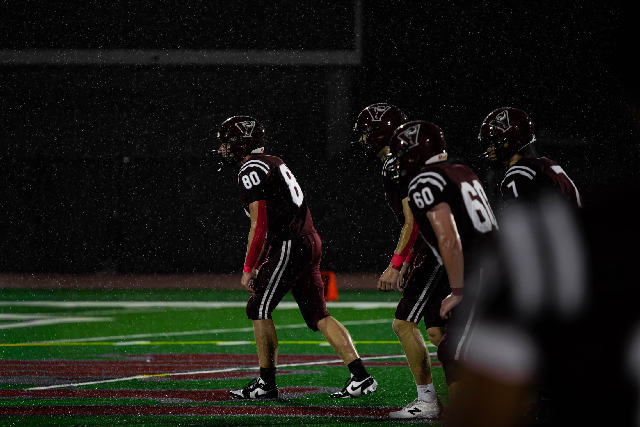East Lyme football players walking across the field in heavy rain under the lights
