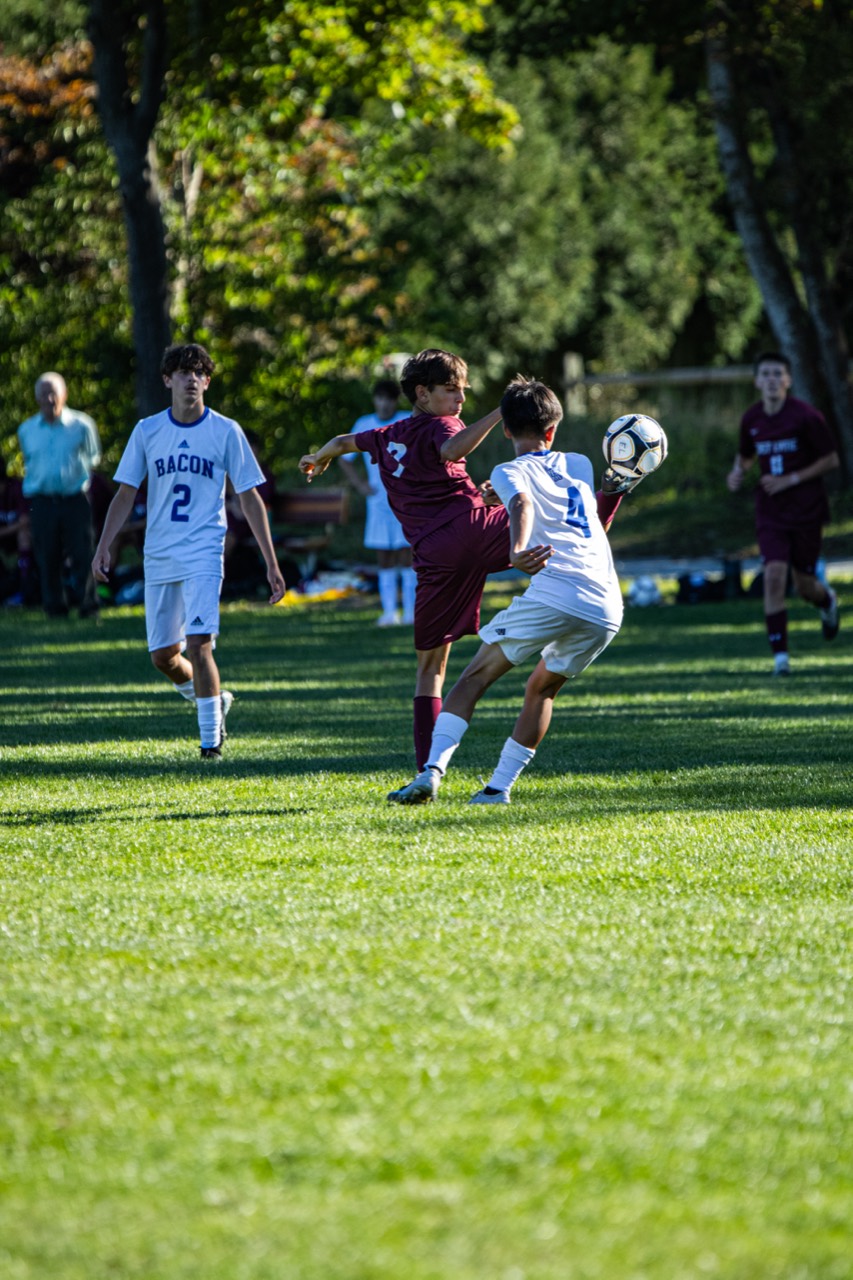 East Lyme soccer player controlling the ball while challenged by a Bacon Academy defender